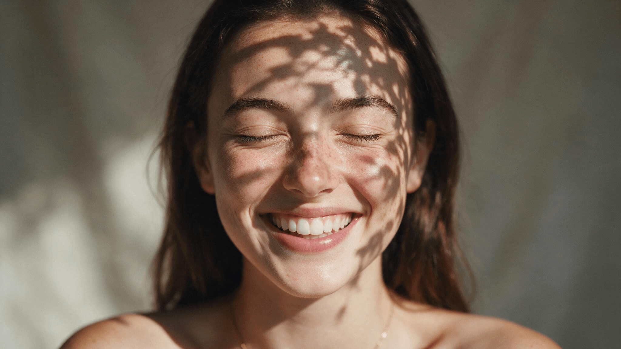 Smiling person shielding one eye in bright daylight